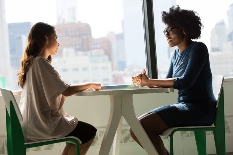 women-conversation-tinnitus Two women having a professional conversation at a table.