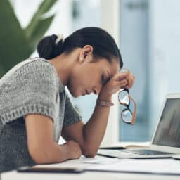 A woman looking distressed next to her laptop computer.