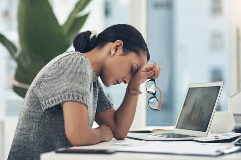 A woman looking distressed next to her laptop computer.