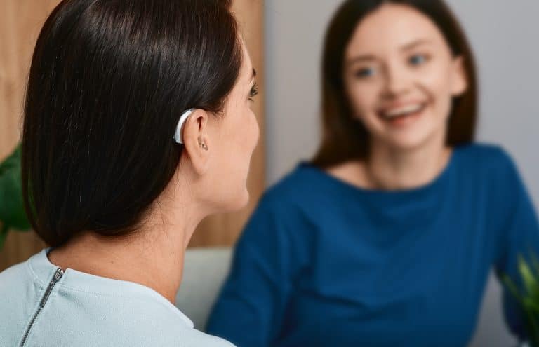 woman-hearing-aids-chatting-speech-recognition Young woman with a hearing aid chats with her friend.