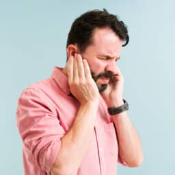 Man with tinnitus holding his ears