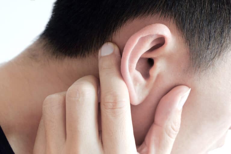 The young man touched his ear and he had a sore ear.