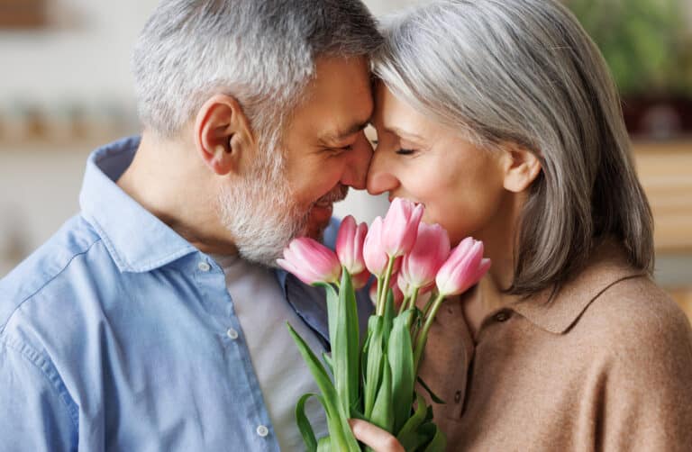 Happy couple hugging and exchanging flowers on Valentine's Day.