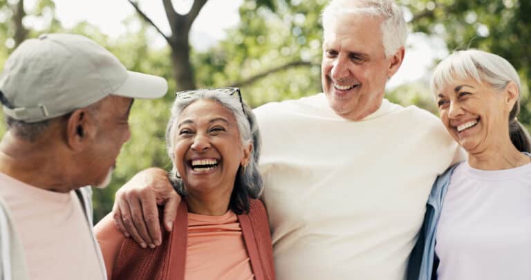 Group of mature adult friends laughing together in a park, enjoying each other's company Group of mature adult friends laughing together in a park, enjoying each other's company